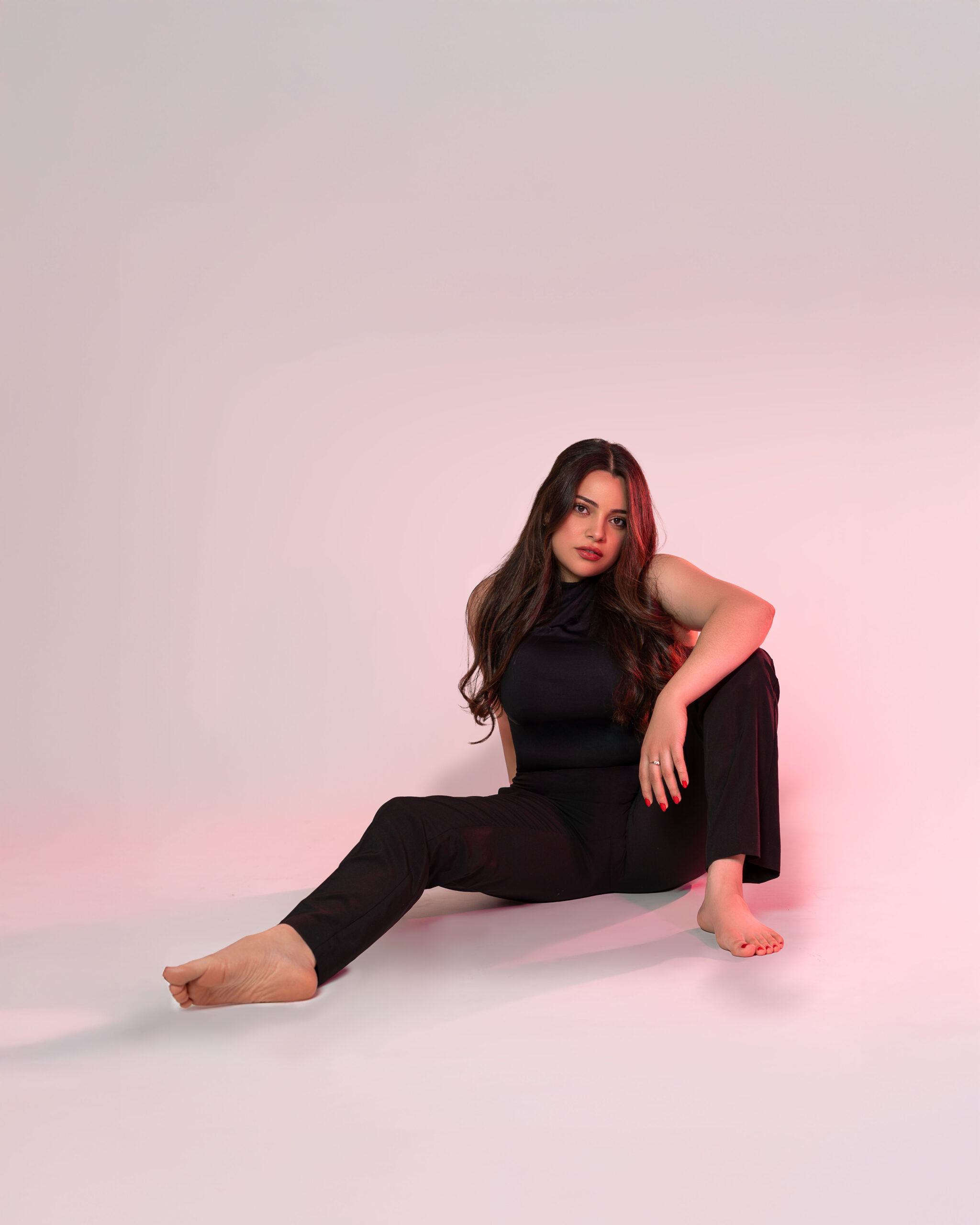 Seated studio portrait against a pink background
